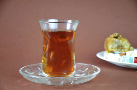 Tasty oriental sweets baklava, turkish delight on a plate on a dark black brown background and glasses of tea.の写真素材