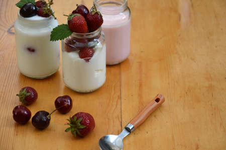 Healthy breakfast home made pudding or yogurt or granola, strawberries, cherry, honeysuckle berry, nuts and yogurt. Vegetarian keto food. Top view pudding or cocktail on background of green foliage.の写真素材