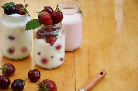 Healthy breakfast home made pudding or yogurt or granola, strawberries, cherry, honeysuckle berry, nuts and yogurt. Vegetarian keto food. Top view pudding or cocktail on background of green foliage.の写真素材