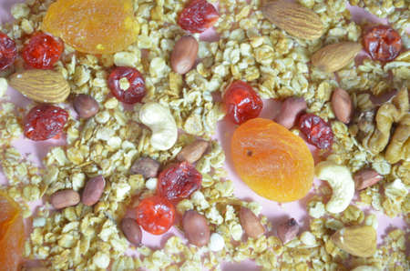 Muesli with dried fruits and nuts, healthy food, on a pink background, abstract background.の写真素材