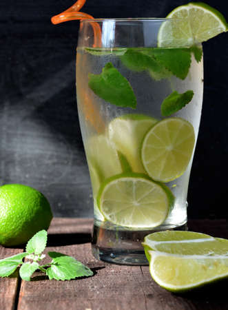 Mojito cocktail on black background with lime and mint with copy space alcoholic or non-alcoholic drink at the bar. summer refreshing cocktail with ice cubes on dark woodenの写真素材