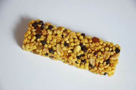 Granola bars, muesli bars or energy bars with oats, dates and nuts on white pink background, close...