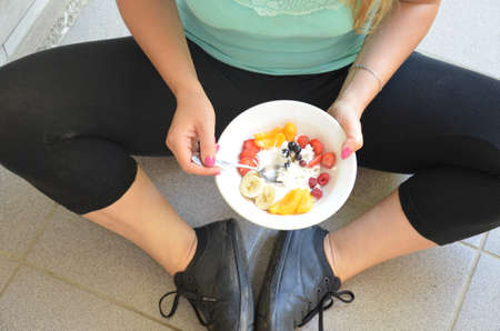 Young woman is resting and eating a healthy salad after a workout. Fitness and healthy lifestyle concept.の写真素材