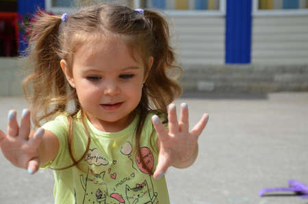 girl shows hands after drawing, stained in chalk. The child draws the house with chalk on the asphalt. Selective focus. draw.の写真素材