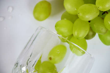 white grapes in a wine glass. White wine in a glass with fall grapes, white background, selective focusの写真素材