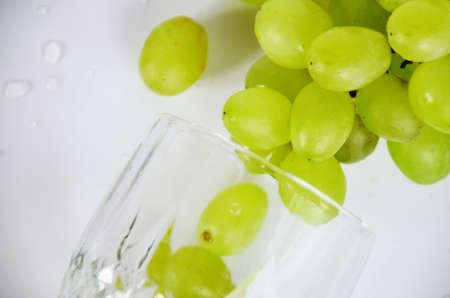 white grapes in a wine glass. White wine in a glass with fall grapes, white background, selective focusの写真素材