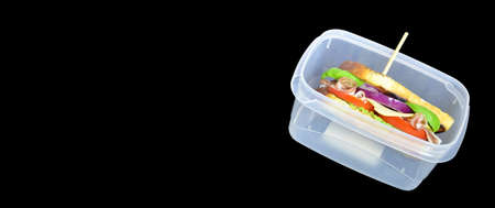 Healthy grilled Sandwich toast with lettuce, ham, cheese and tomato on a dark black background close up. Lunch box with sandwich concept back to school on school blackboard bannerの写真素材