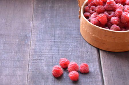 Fresh ripe raspberries in the wicker basket on wooden tableの写真素材