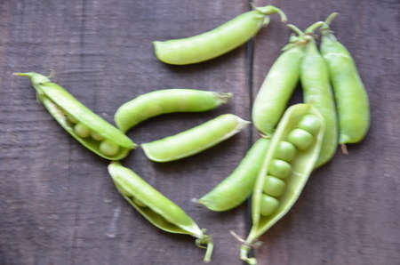fresh green peas, just harvest. close up view of opened pod. spring vegetable up view on the wooden backgroundの写真素材