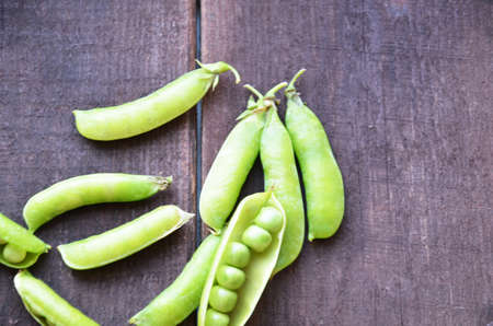 fresh green peas, just harvest. close up view of opened pod. spring vegetable up view on the wooden backgroundの写真素材