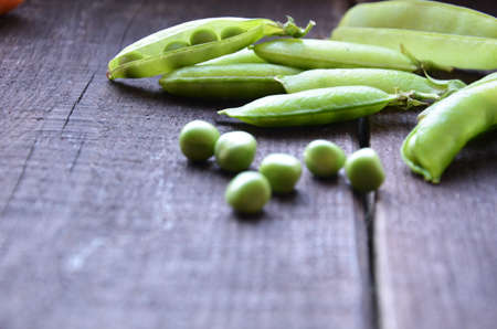 fresh green peas, just harvest. close up view of opened pod. spring vegetable up view on the wooden backgroundの写真素材