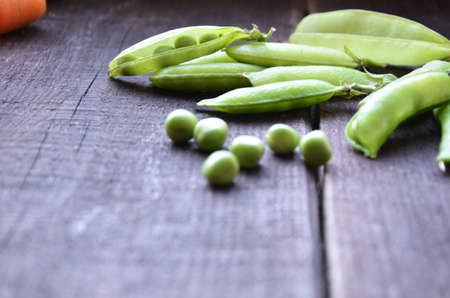fresh green peas, just harvest. close up view of opened pod. spring vegetable up view on the wooden backgroundの写真素材