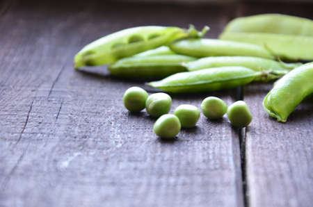 fresh green peas, just harvest. close up view of opened pod. spring vegetable up view on the wooden backgroundの写真素材