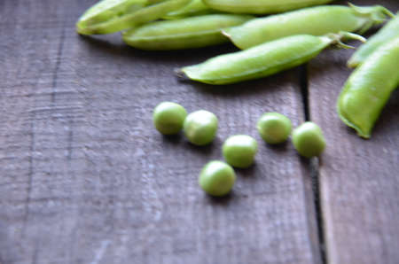 fresh green peas, just harvest. close up view of opened pod. spring vegetable up view on the wooden backgroundの写真素材