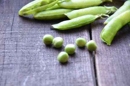 fresh green peas, just harvest. close up view of opened pod. spring vegetable up view on the wooden backgroundの写真素材