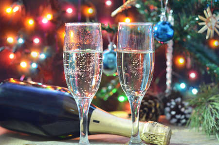 two glasses of champagne on the background of champagne. Christmas tree with Christmas lights. New Year and Christmas. Gift boxes tied with bowsの写真素材