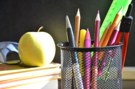 Back to school. pens, pencils, brushes in a glass against the background of a blackboard. School background with space for your textの写真素材