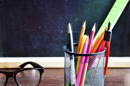 Back to school. pens, pencils, brushes in a glass against the background of a blackboard. School background with space for your textの写真素材
