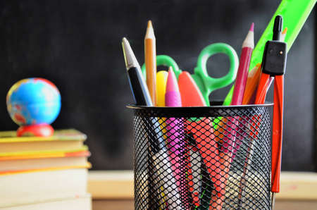 Back to school. pens, pencils, brushes in a glass against the background of a blackboard. School background with space for your textの写真素材