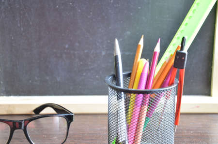Back to school. pens, pencils, brushes in a glass against the background of a blackboard. School background with space for your textの写真素材