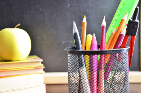 Back to school. pens, pencils, brushes in a glass against the background of a blackboard. School background with space for your textの写真素材
