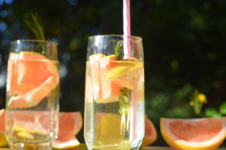 Girl cooking healthy detox smoothie with fresh fruits and green rosemary grapefruit water. Lifestyle detox conceptの写真素材