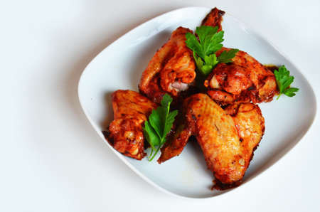 plate of chicken wings on white table red sauce in a gravy boatの写真素材