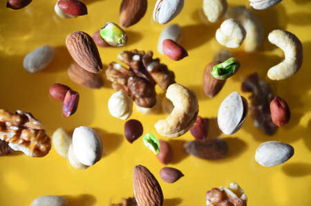 Nuts in the air on a yellow background, flying nuts. Healthy Brain Food, Diet, Protein, Almonds, walnuts and hazelnuts peanut, cashews, pistachiosの写真素材