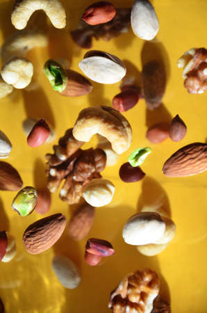Nuts in the air on a yellow background, flying nuts. Healthy Brain Food, Diet, Protein, Almonds, walnuts and hazelnuts peanut, cashews, pistachiosの写真素材