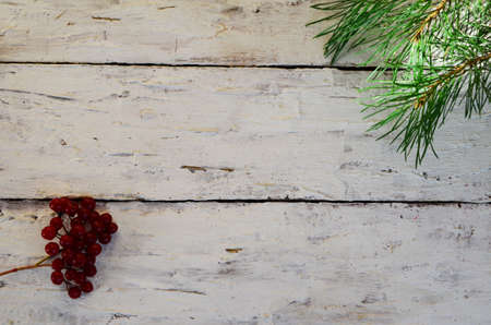 Merry Christmas and Happy New Year a branch of a Christmas tree with cones in the snow on a white wooden background with red berries then view flat lay copy spaceの写真素材