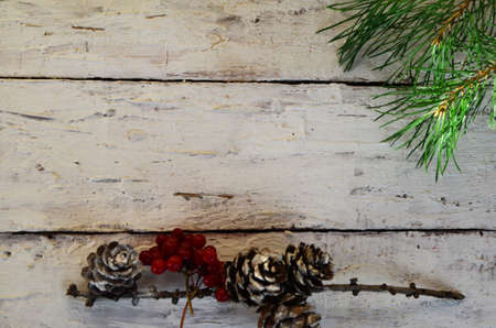 Merry Christmas and Happy New Year a branch of a Christmas tree with cones in the snow on a white wooden background with red berries then view flat lay copy spaceの写真素材