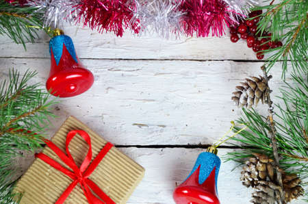 Christmas or new year composition. Christmas gift, two Christmas decorations red blue bell, pine cones, fir branches on wooden white background. Flat lay, top view, copy spaceの写真素材