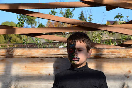 boy with black makeup for halloween, zombie. Scary little boy smiling wearing skull makeup for halloweenの写真素材