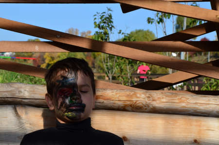 boy with black makeup for halloween, zombie. Scary little boy smiling wearing skull makeup for halloweenの写真素材