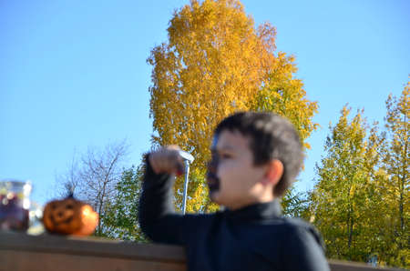 boy with black makeup for halloween, zombie. Scary little boy smiling wearing skull makeup for halloween halloween pumpkin lantern, sweetsの写真素材