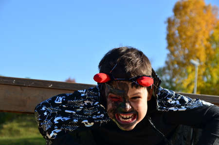 funny baby in devil halloween costume with horns and trident on a dark wooden background boy with black makeup for halloween, zombieの写真素材