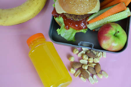 Homemade Hamburgers with lettuce in lunchbox on the table. with bright yellow orange juice. with...