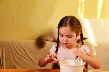 Cute little girl is playing and laughing while kneading the dough in the kitchenの写真素材