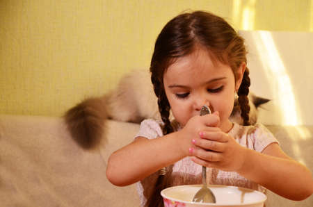 Cute little girl is playing and laughing while kneading the dough in the kitchenの写真素材