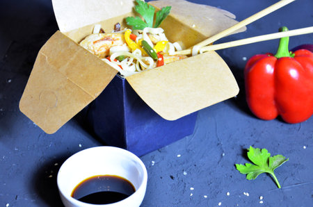 Asian food and chopsticks on wooden table. takeout boxes with noodles with chicken meat and rice with seafood cocktail and vegetables. Fast food delivery.の写真素材