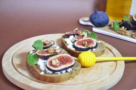 Sandwiches with ricotta, fresh figs, walnuts and honey. Canape or crostini with toasted baguette, cheese, jam, Delicious appetizer, ideal as an aperitif. Selective focusの写真素材