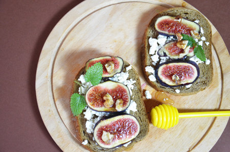 Sandwiches with ricotta, fresh figs, walnuts and honey. Canape or crostini with toasted baguette, cheese, jam, Delicious appetizer, ideal as an aperitif. Selective focusの写真素材