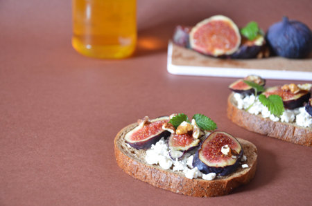 Sandwiches with ricotta, fresh figs, walnuts and honey. Canape or crostini with toasted baguette, cheese, jam, Delicious appetizer, ideal as an aperitif. Selective focusの写真素材