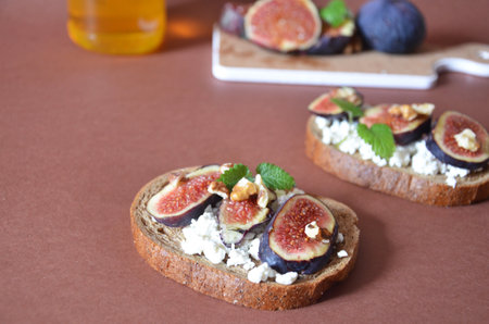 Sandwiches with ricotta, fresh figs, walnuts and honey. Canape or crostini with toasted baguette, cheese, jam, Delicious appetizer, ideal as an aperitif. Selective focusの写真素材