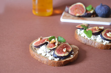 Sandwiches with ricotta, fresh figs, walnuts and honey. Canape or crostini with toasted baguette, cheese, jam, Delicious appetizer, ideal as an aperitif. Selective focusの写真素材