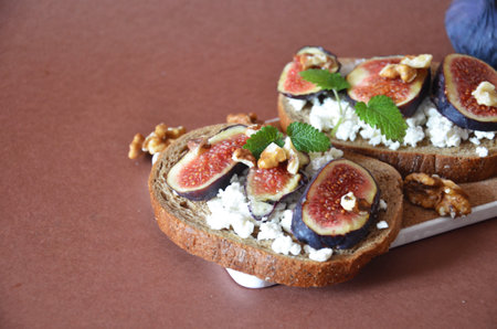 Sandwiches with ricotta, fresh figs, walnuts and honey. Canape or crostini with toasted baguette, cheese, jam, Delicious appetizer, ideal as an aperitif. Selective focusの写真素材