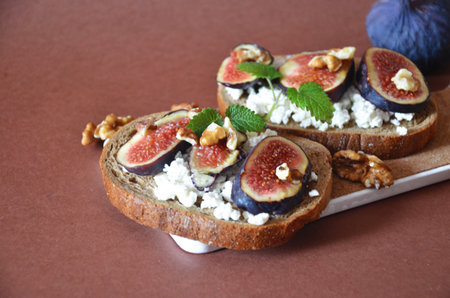 Sandwiches with ricotta, fresh figs, walnuts and honey. Canape or crostini with toasted baguette, cheese, jam, Delicious appetizer, ideal as an aperitif. Selective focusの写真素材