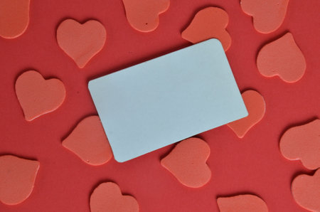 Festive holiday greeting card for Valentines, Birthday, Woman, Mothers Day. Red white hearts and empty card on red background. Valentines day concept. Flat lay, top view, copy space.の写真素材