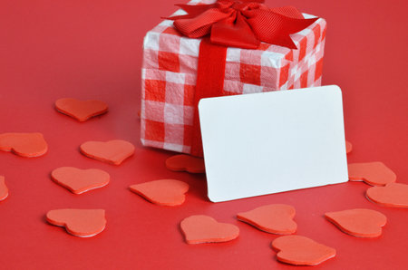 Festive holiday greeting card for Valentines, Birthday, Woman, Mothers Day. Red white hearts and empty card on red background. Valentines day concept. Flat lay, top view, copy space.の写真素材