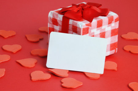 Festive holiday greeting card for Valentines, Birthday, Woman, Mothers Day. Red white hearts and empty card on red background. Valentines day concept. Flat lay, top view, copy space.の写真素材